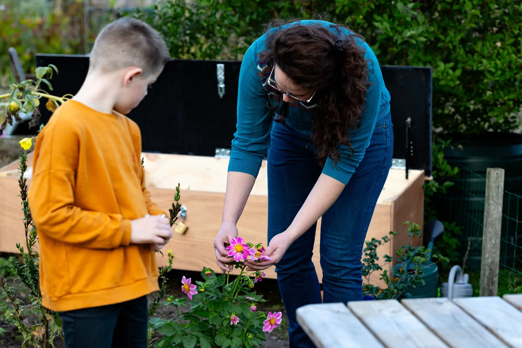 Moeder en zoon verzamelen bloemen naast de moestuin