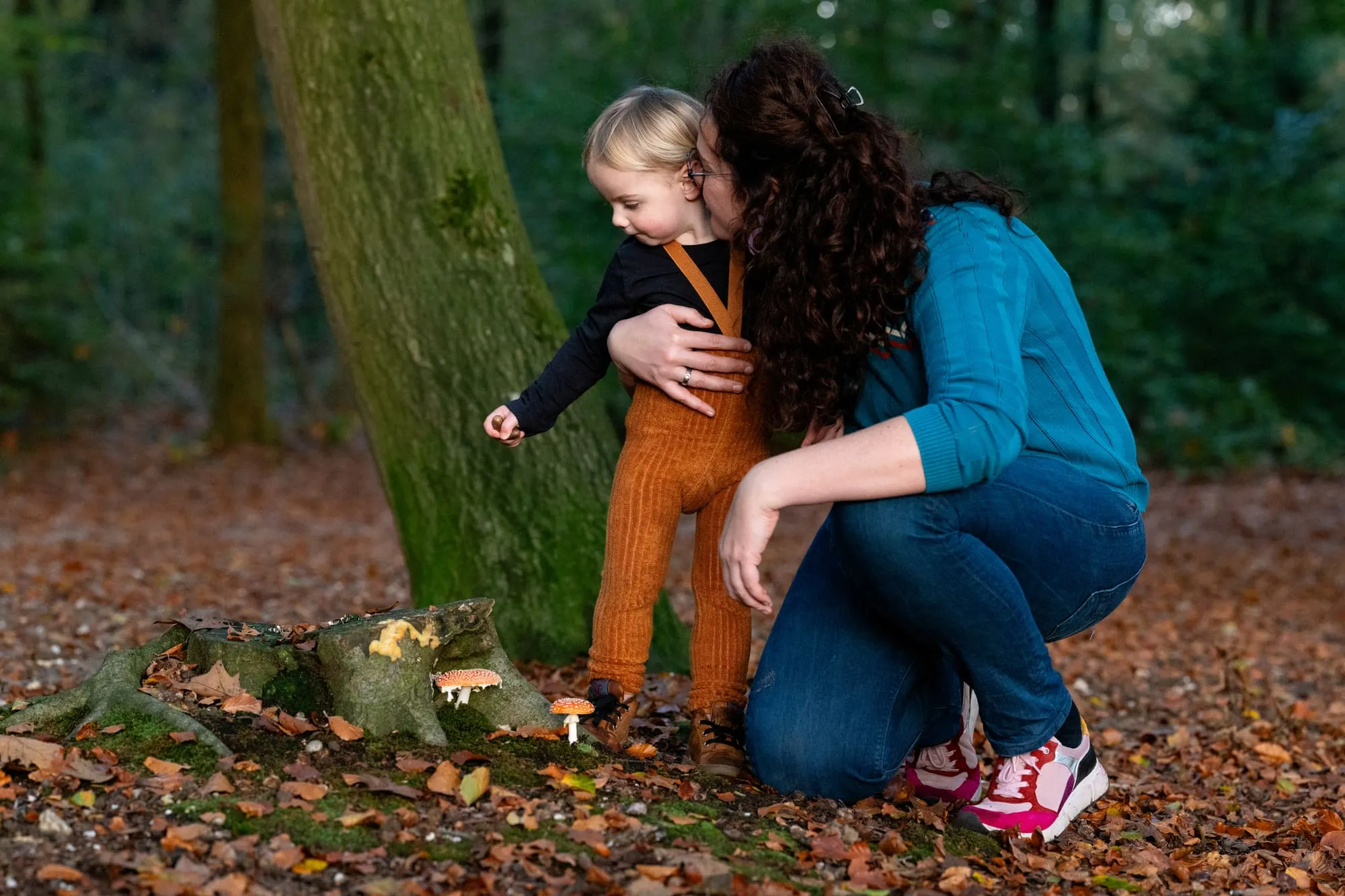 Moeder knuffelt haar dochter bij een boom in het herfstbos