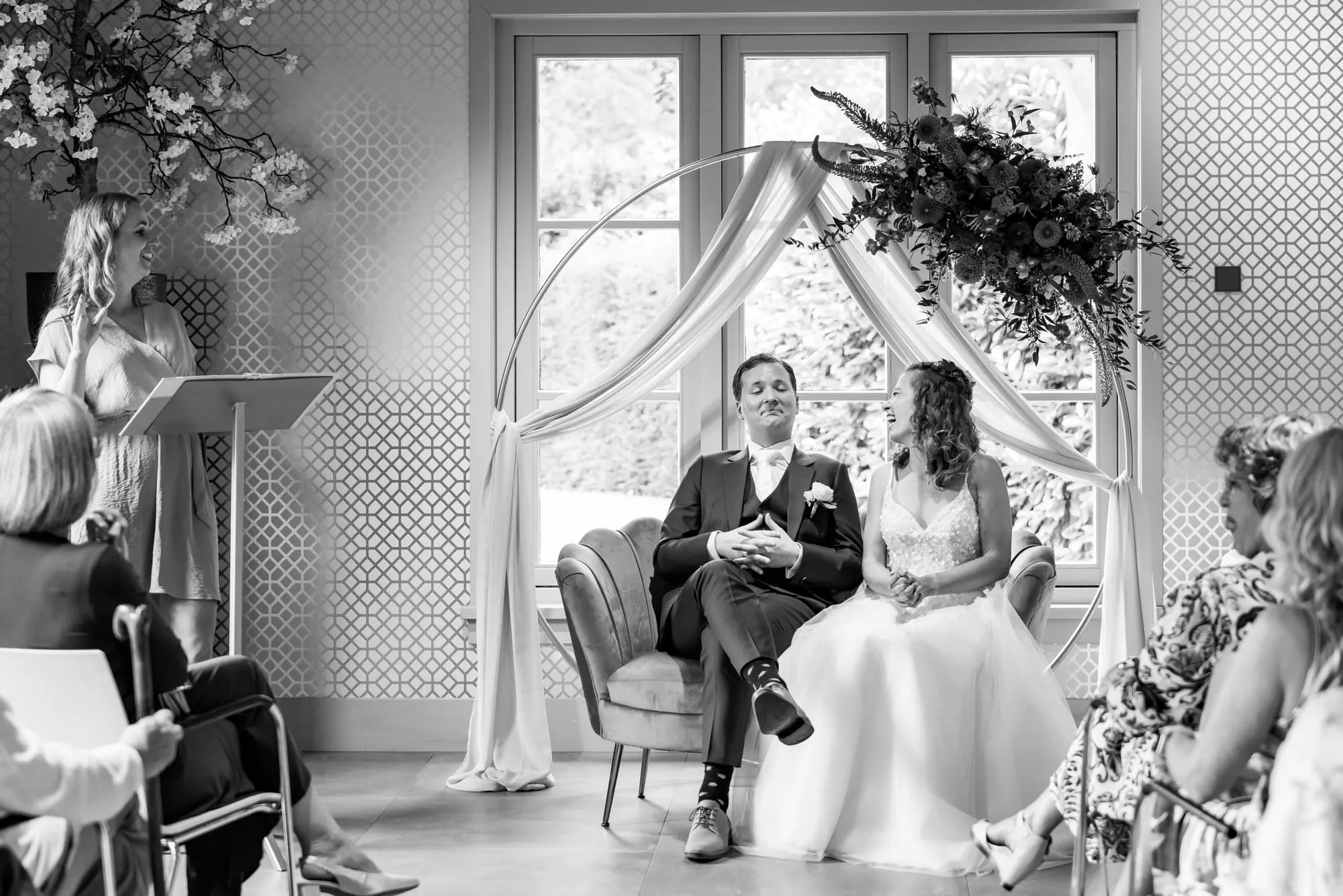 Zwart-witbeeld van het bruidspaar tijdens de ceremonie in het koetshuis