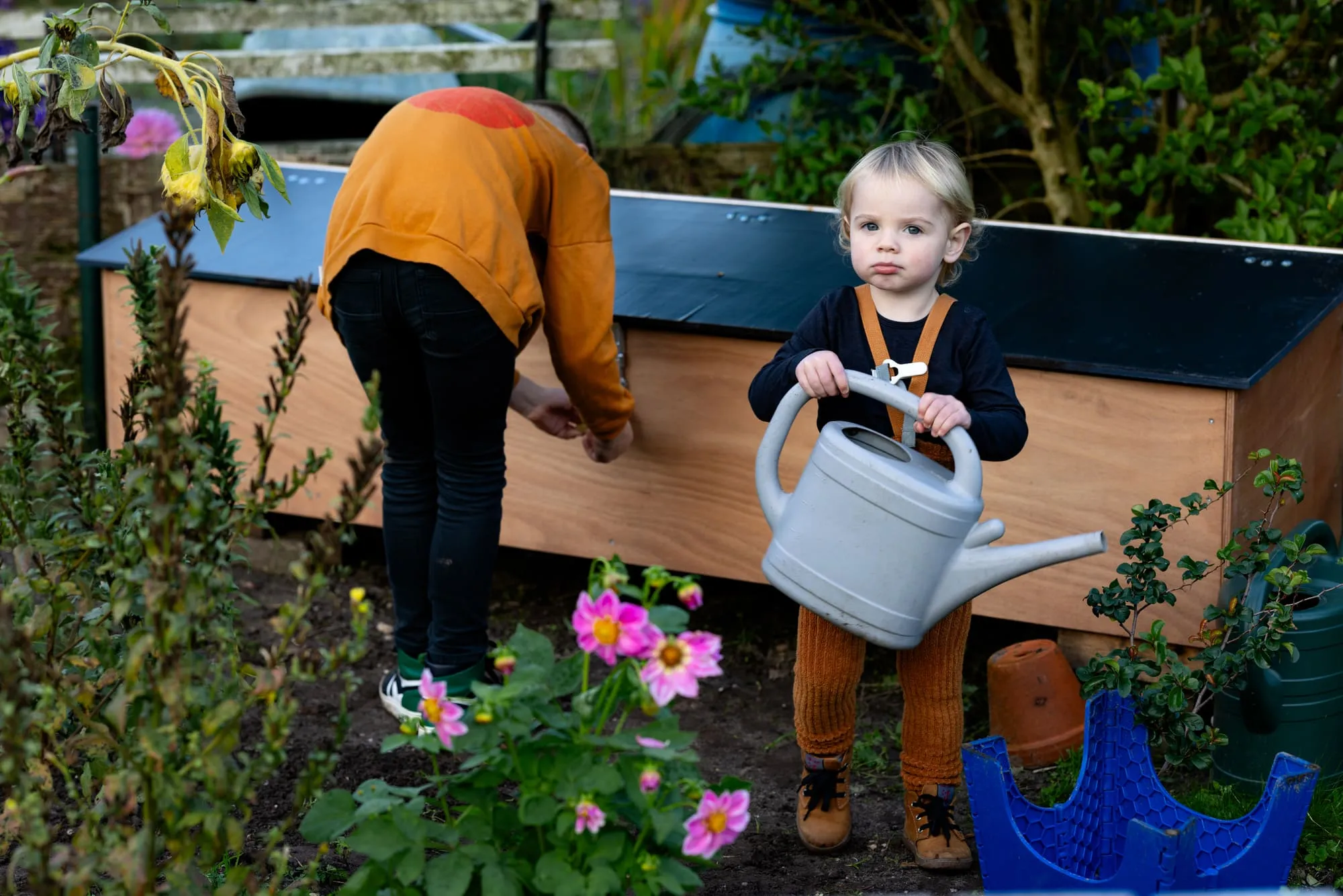 Een meisje houdt een gieter vast tussen de bloemen