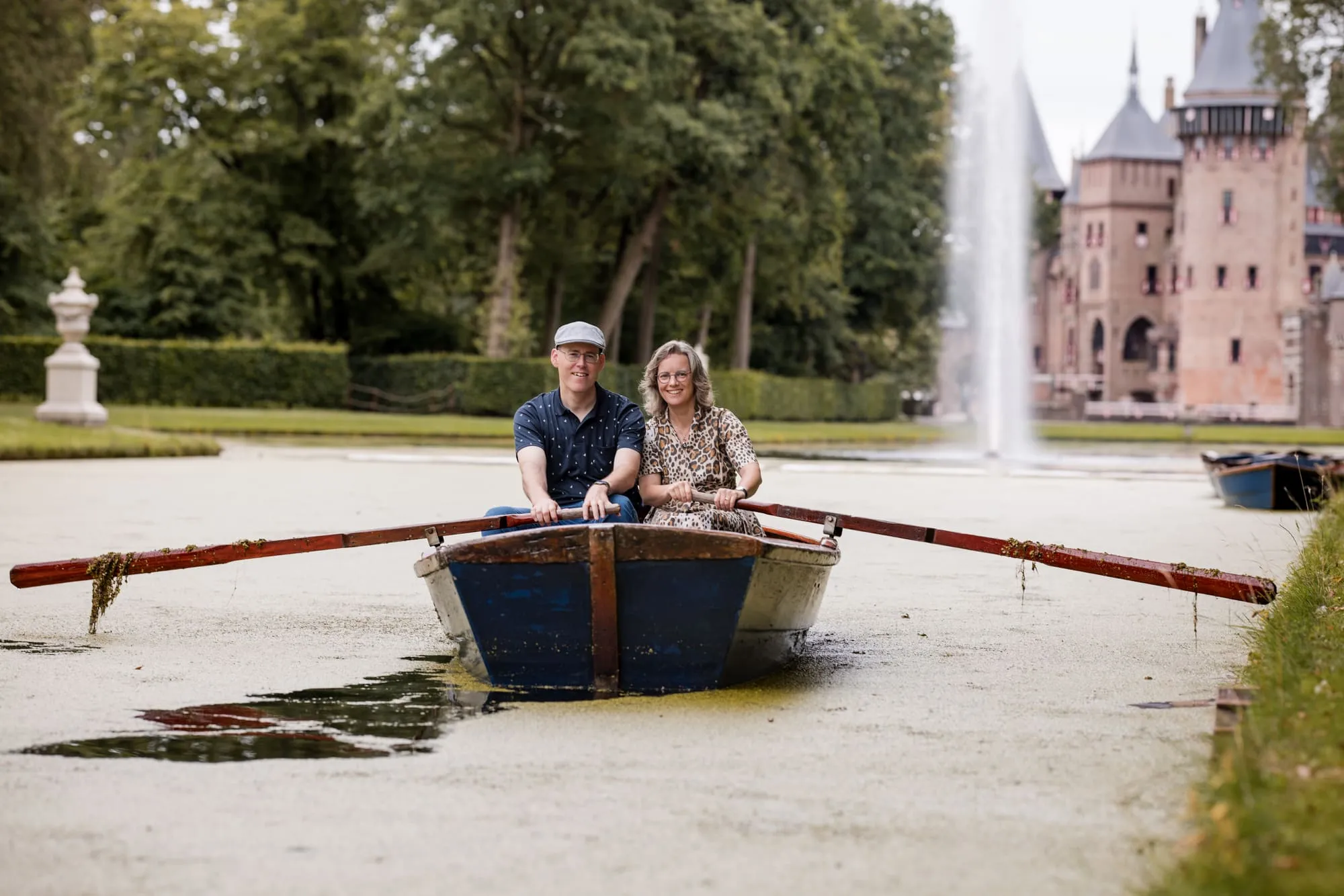 De roeiboot ligt stil voor de fontein, met het kasteel op de achtergrond