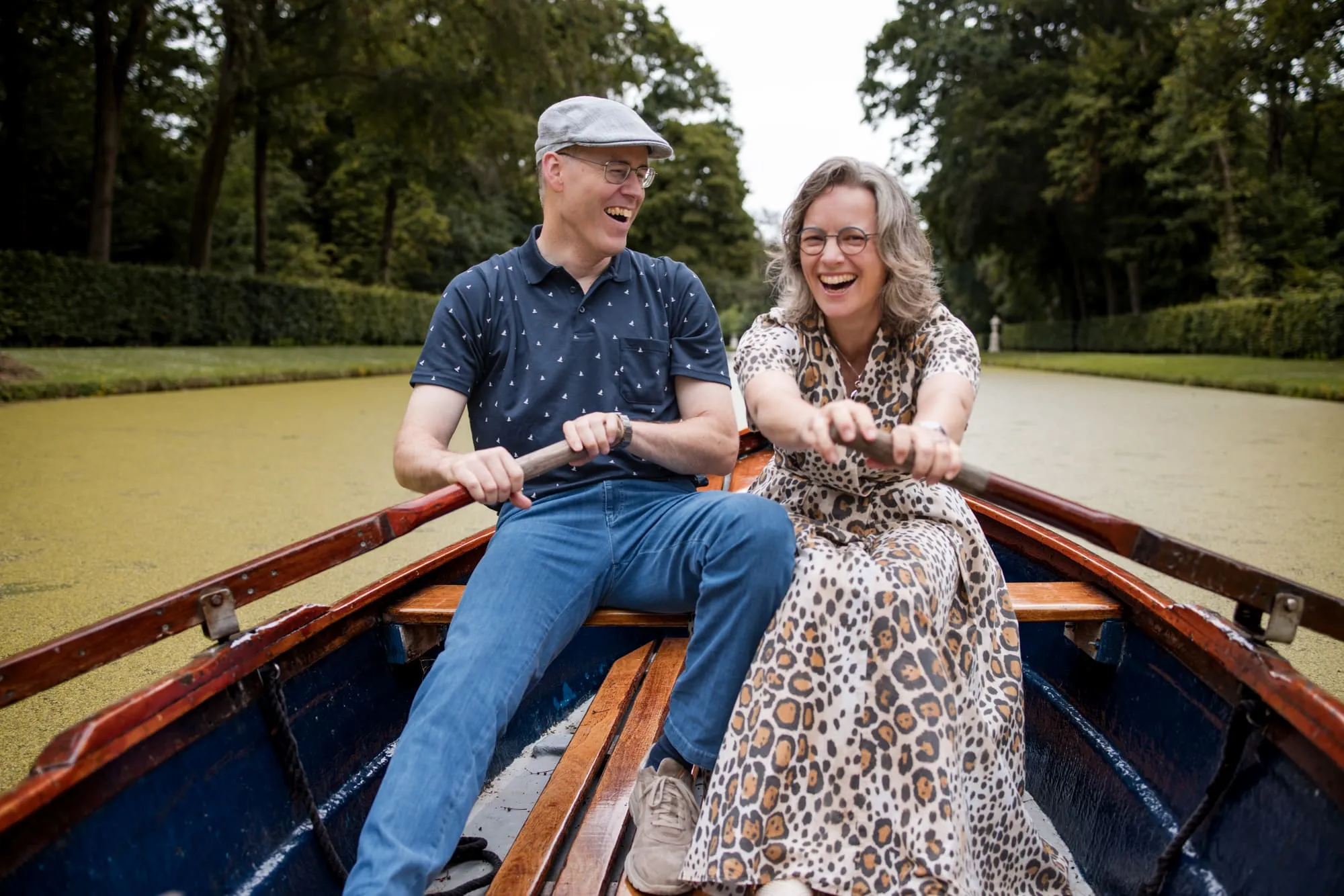 Het stel roeit lachend samen in een houten roeiboot door de kasteelgracht