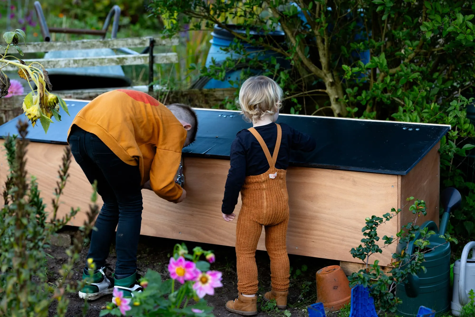 Twee kinderen kijken nieuwsgierig in een moestuinbak