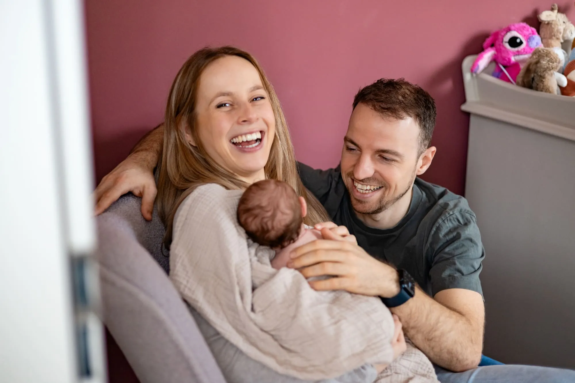 Ouders zitten samen op de bank met hun pasgeboren baby op schoot