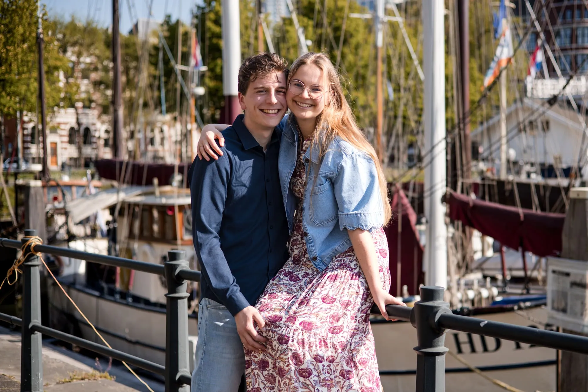 Het stel staat gearmd op de kade tussen de historische zeilschepen