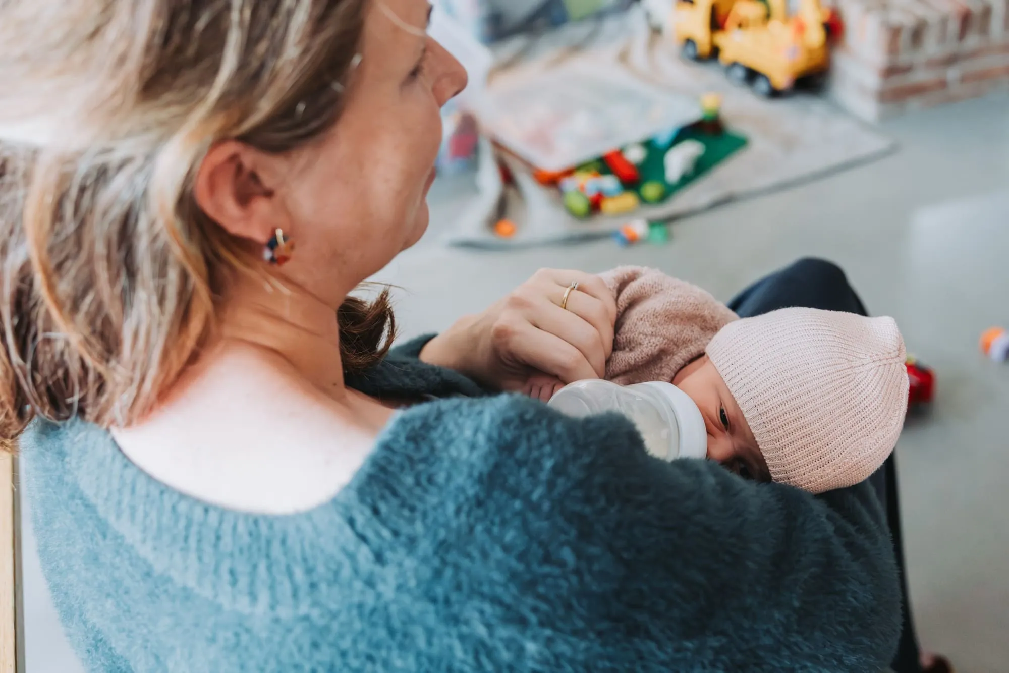 Moeder geeft de baby de fles aan de speeltafel